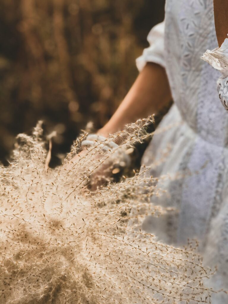 Close-up of a woman holding wildflowers in a white dress, capturing a serene outdoor moment.